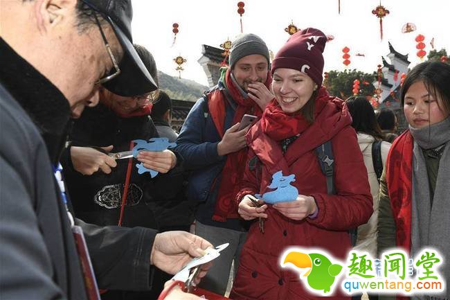 2月4日，来自乌克兰的尤妮亚（前右二）在手艺人的指导下学习剪窗花。春节临近，近100位外国友人应邀来到浙江省宁波市奉化区尚田镇鸣雁村，体验舞龙、写春联、打年糕、剪窗花等传统民俗活动，迎接新春佳节。   新华社记者 黄宗治 摄